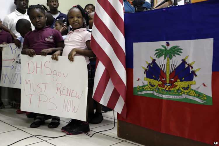 Los niños se paran junto a banderas de Estados Unidos y Haití mientras sostienen carteles en apoyo de la renovación del Estatus de Protección Temporal (TPS) para inmigrantes de América Central y Haití que ahora viven en los Estados Unidos, durante una conferencia de prensa el 6 de noviembre de 2017, en Miami.