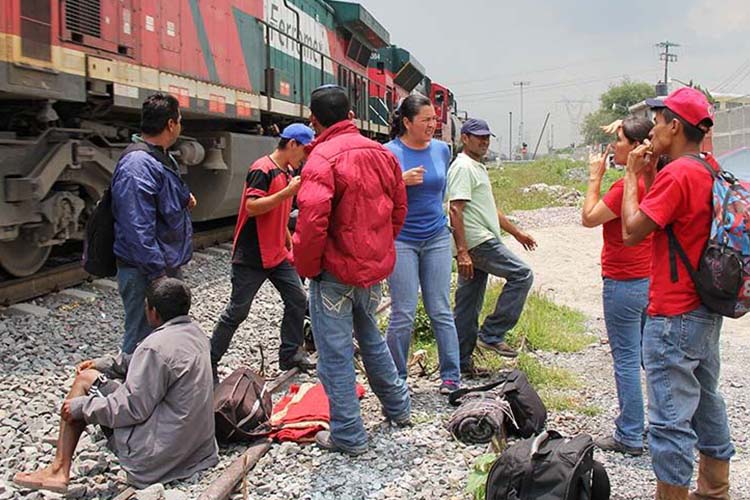Migrantes al pie del tren de carga, al que se suben para cruzar México de sur a norte. Foto: Cortesía CRS.