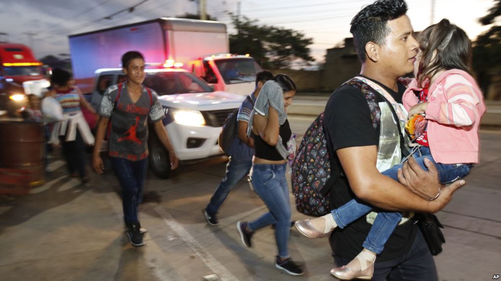 Decenas de migrantes que buscan llegar a Estados Unidos caminan por una carretera mientras salen de San Pedro Sula, Honduras, al amanecer del martes. | Foto: Voz de América