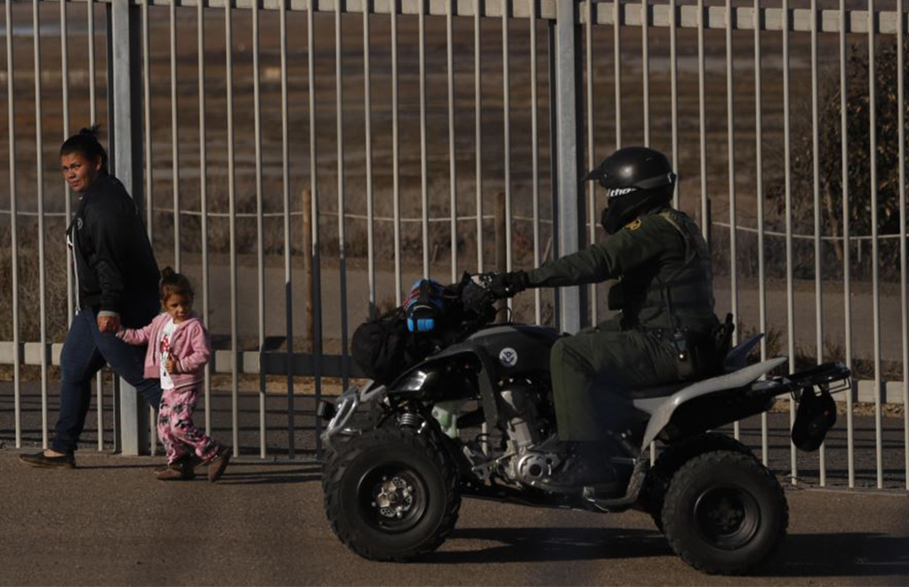 Archivo - Rachel Rivera, migrante hondureña de 19 años, y su hija, Charlot Andrea, de 3 años, caminan a lo largo de la valla fronteriza en San Ysidiro, California, tras entregarse a agentes de la Patrulla Fronteriza de EE.UU. el 4 de diciembre de 2018. | Foro: Voz de América / AP