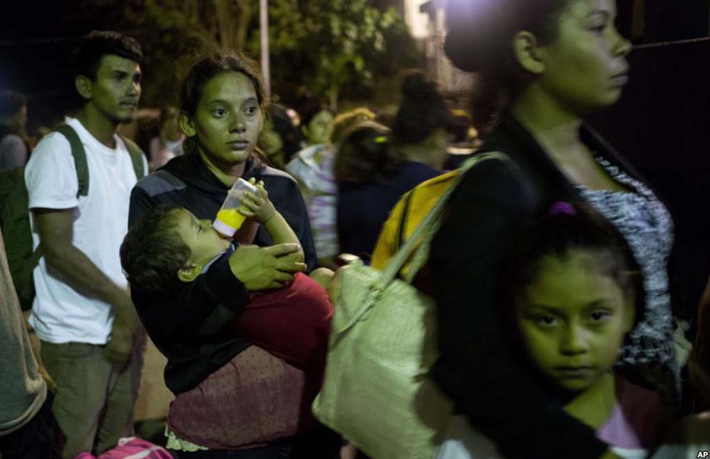 Glasys Menjiva lleva en brazos a su hijo de 16 meses mientras aguarda en la línea para cruzar la frontera en Agua Caliente, Guatemala. Ella forma parte de la caravana de migrantes que inició el viaje rumbo a EE.UU. el martes.