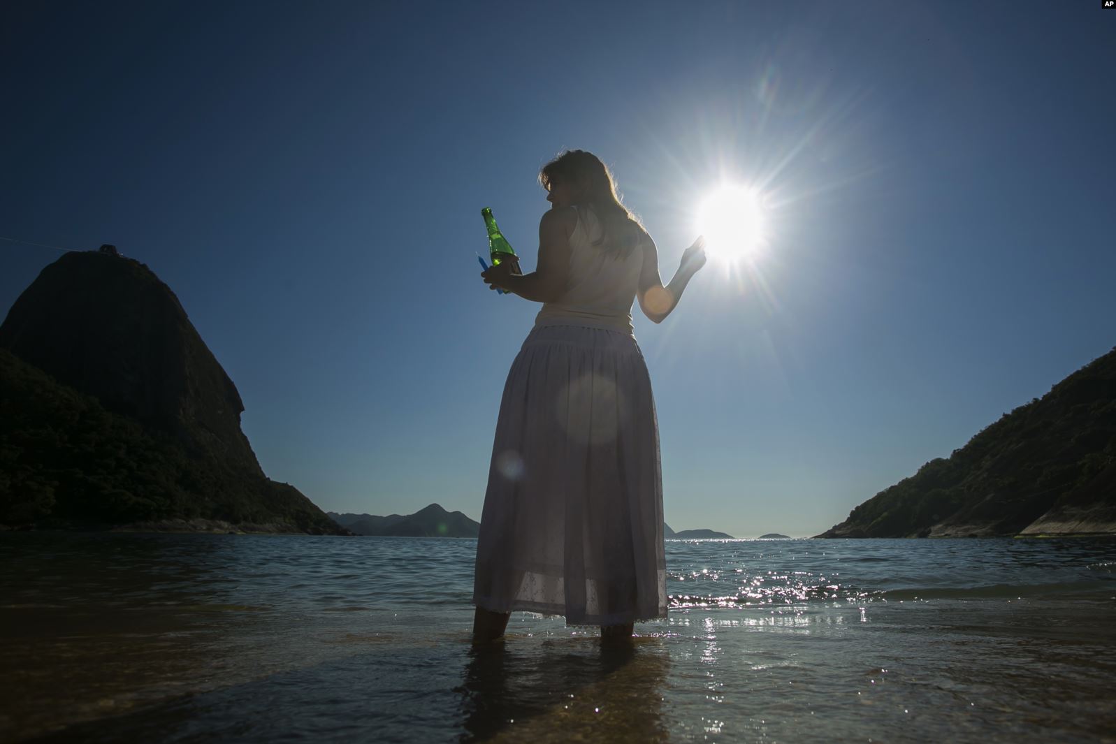 Una mujer sostiene una botella de sidra espumante como una ofrenda a Yemayá, una deidad de la religión africana Yoruba, durante una ceremonia en honor a la diosa del mar, la cual es parte de la celebración en Praia Vermelha, en Rio de Janeiro, Brasil, el 31 de diciembre de 2019. | Foto: AP / Voz de América