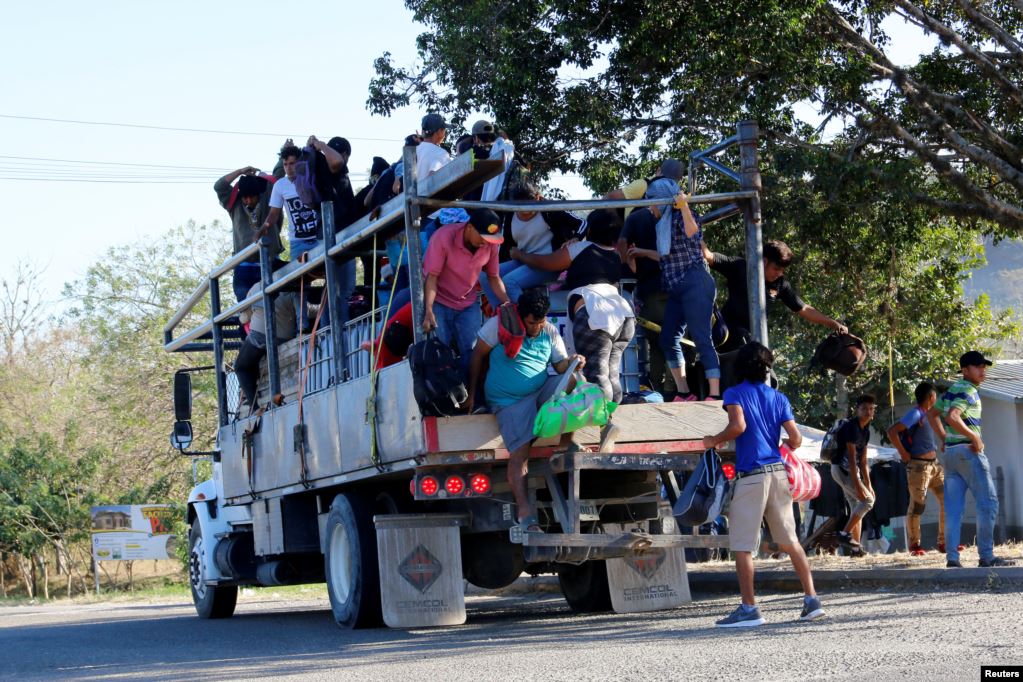 Un grupo de hondureños se suben a un camión para continuar su viaje hacia Estados Unidos.