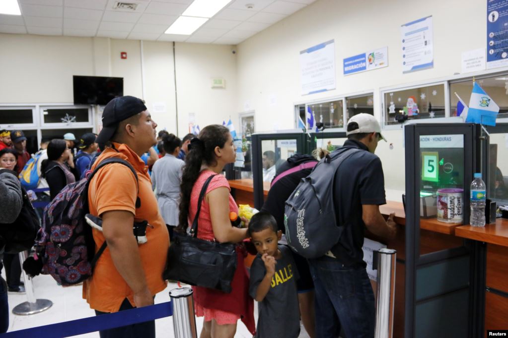 Los migrantes esperan ser registrados por un funcionario de inmigración en la frontera entre Honduras y Guatemala.