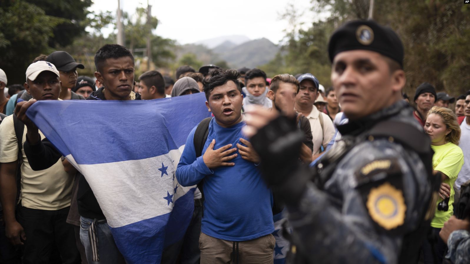Migrantes hondureños, enarbolando la bandera de su país, se detienen ante policías guatemaltecos cerca de Agua Caliente, Guatemala, el 16 de enero de 2020. | Foto: AP / Voz de América