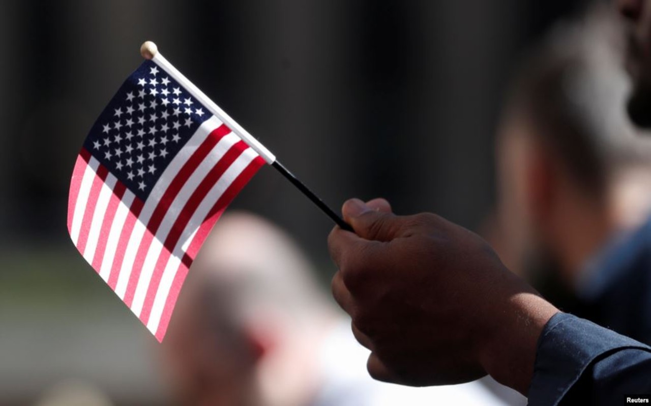 Persona sostiene una pequeña bandera de Estados Unidos
