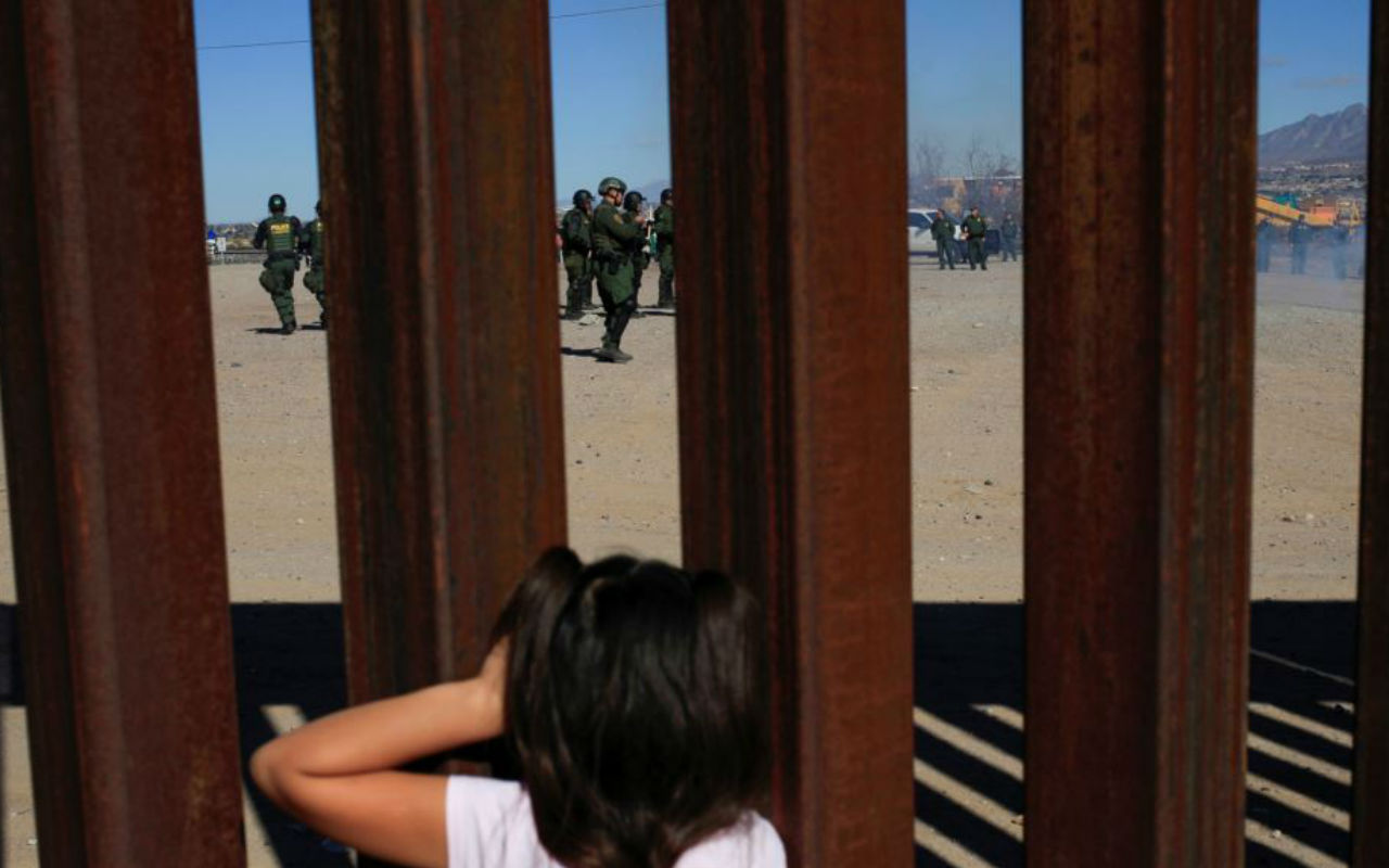 Niña en el muro fronterizo frente a agentes de la CBP Reuters VOA