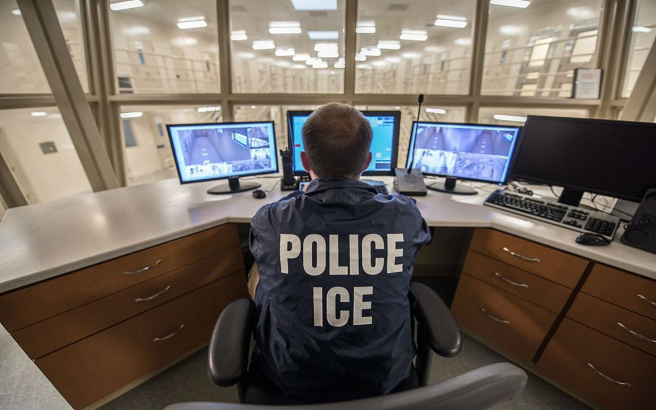 Agente de ICE frente a pantallas con datos