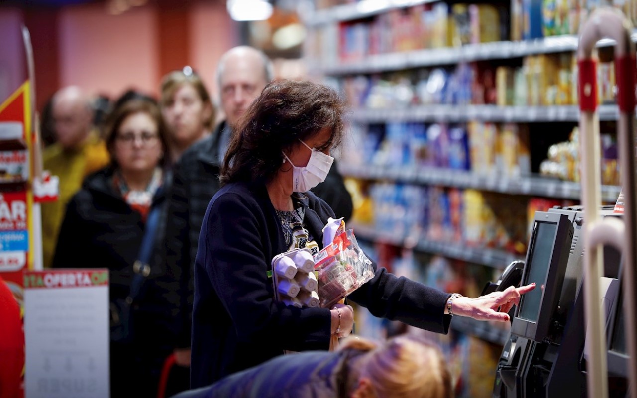 Mujer con cubreboca comprando alimentos en un supermercado