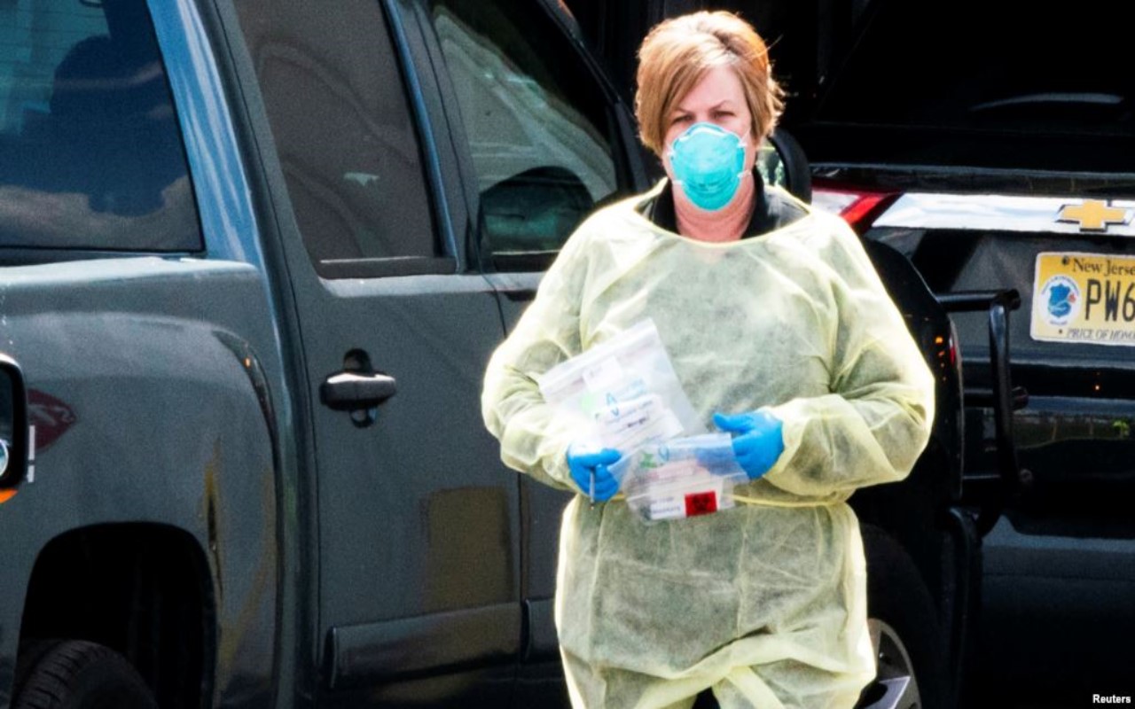 Mujer con cubreboca , guantes y bata para evitar contagio de Covid-19 en EU