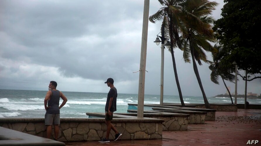 Los hombres miran el mar durante la presencia de la tormenta Isaías en Santo Domingo antes de que se convirtiera en huracán. Foto: VOA, AFP