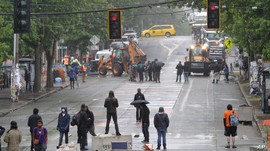 Manifestantes forman barricadas mientras personal del Departamento de Transporte de Seattle remueven otras barricadas en la 10th Ave. y Pine St., en Seattle, Washington, el 30 de junio de 2020. Foto: Voz de América