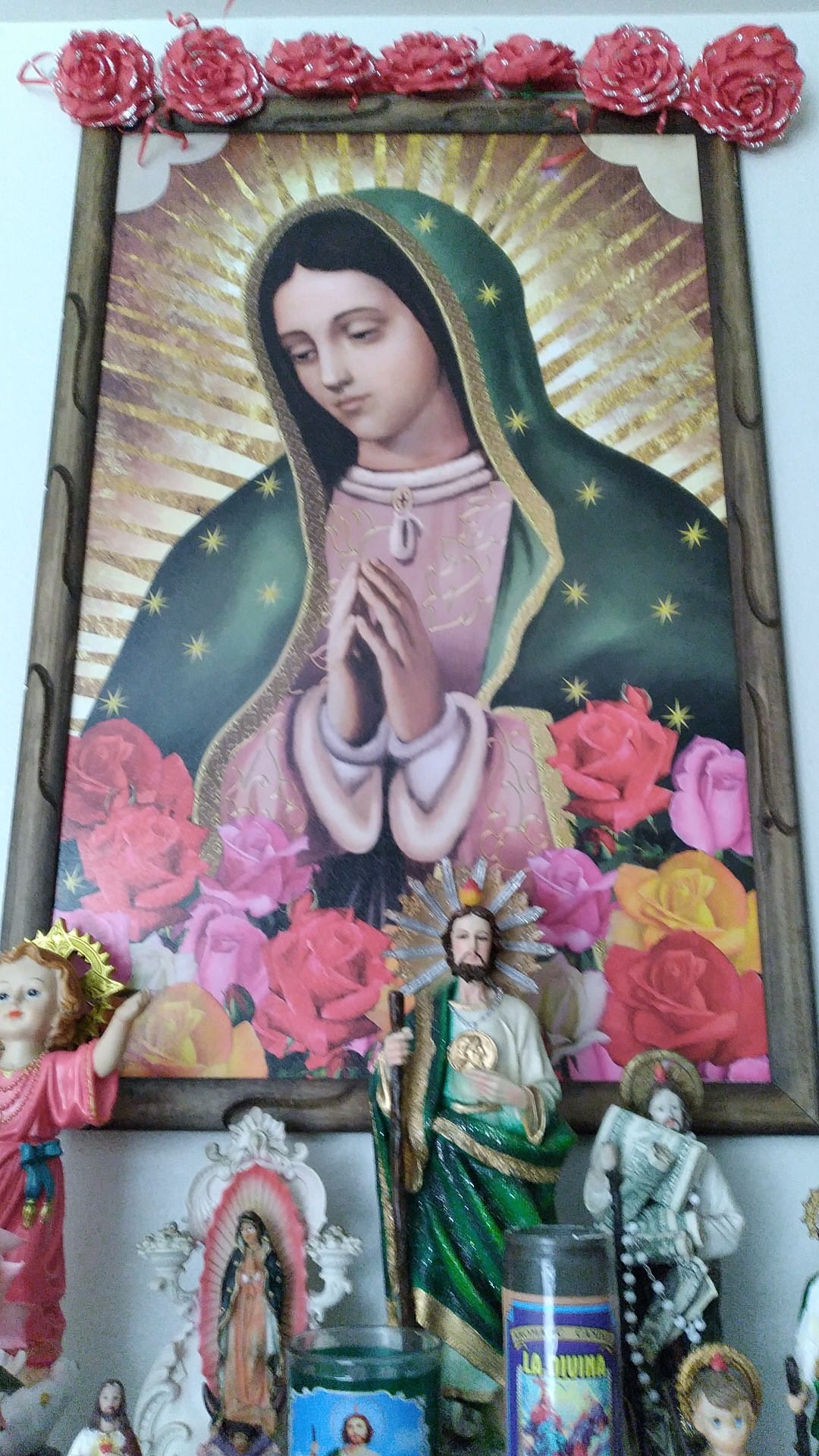 Cuadro al centro de Virgen de Guadalupe con imágenes de Santo niño de Atocha, San Judas Tadeo y veladoras en la parte de abajo