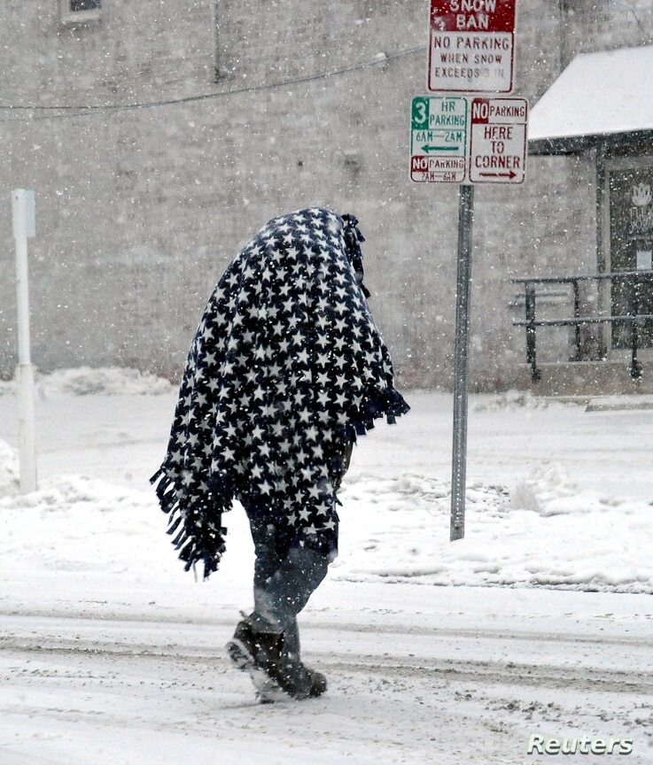 Una persona camina cubierta por una manta pesada para mantenerse caliente después de una tormenta de nieve en el centro de Wooster, Ohio, el 15 de febrero de 2021. | Foto: Reuters / VOA.