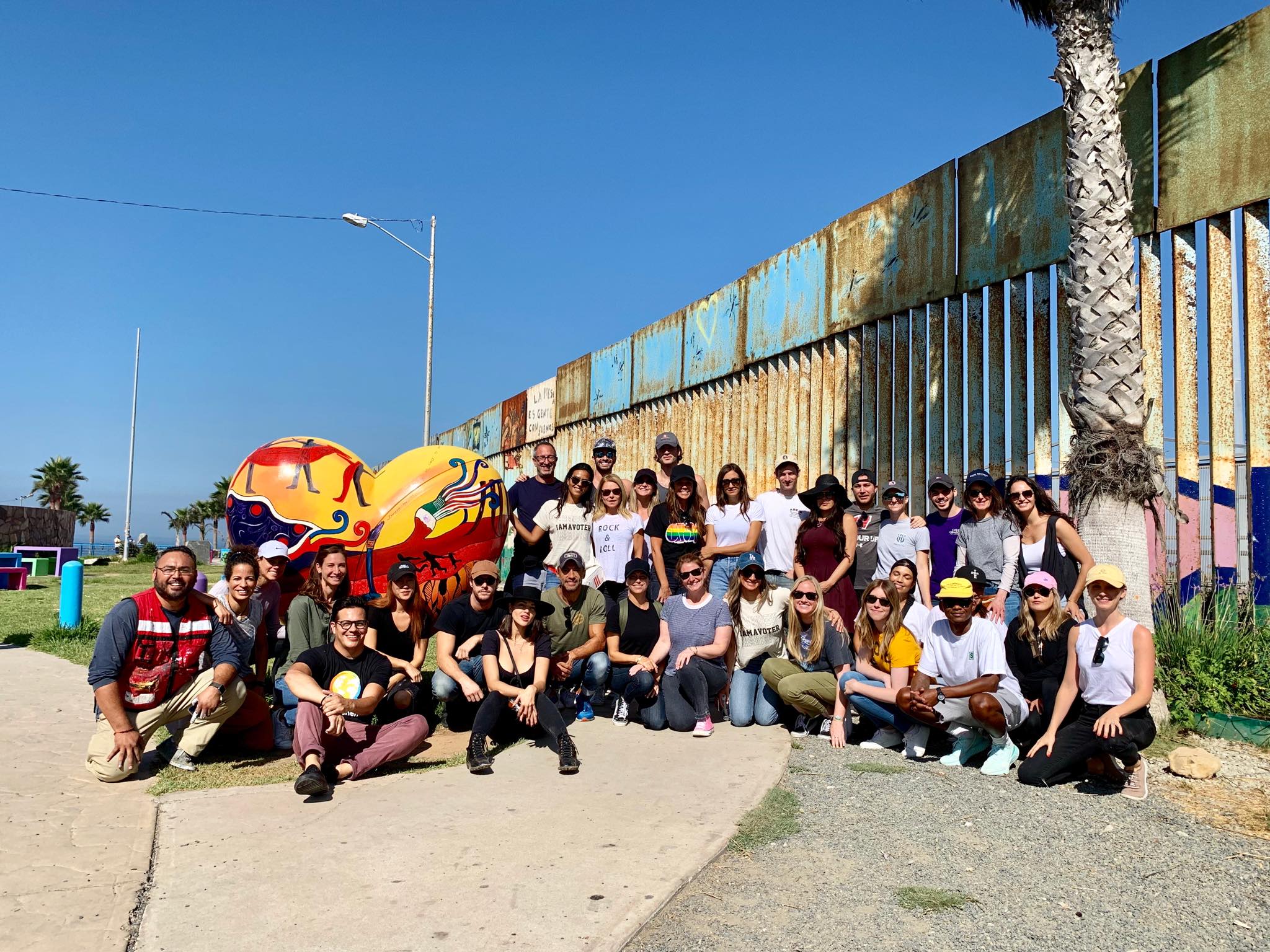 Enrique Chiu y personas pintando en el muro fronterizo
