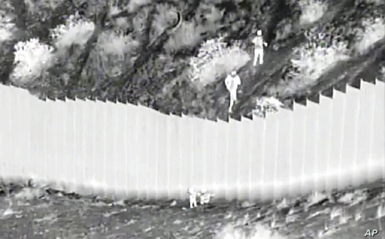 Captura de pantalla de un video de la Oficina de Aduanas y Protección Fronteriza capta el momento en el que traficantes lanzan a dos niñas desde lo alto del muro fronterizo con México en Santa Teresa, Nuevo México, el 30 de marzo de 2021. | VOA/AP.
