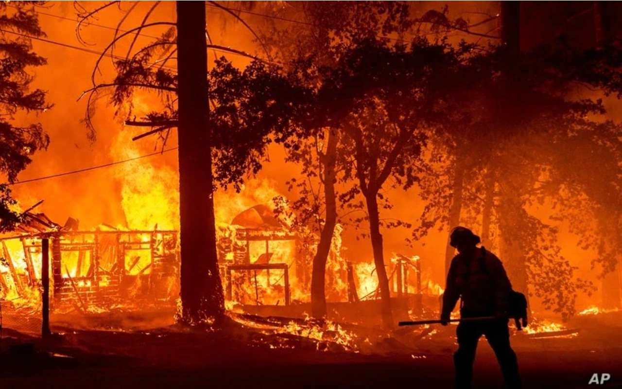 Un bombero pasa junto a una casa en llamas en un incendio en el condado de Plumas, California, el 24 de julio de 2021. | Foto: AP / Voz de América