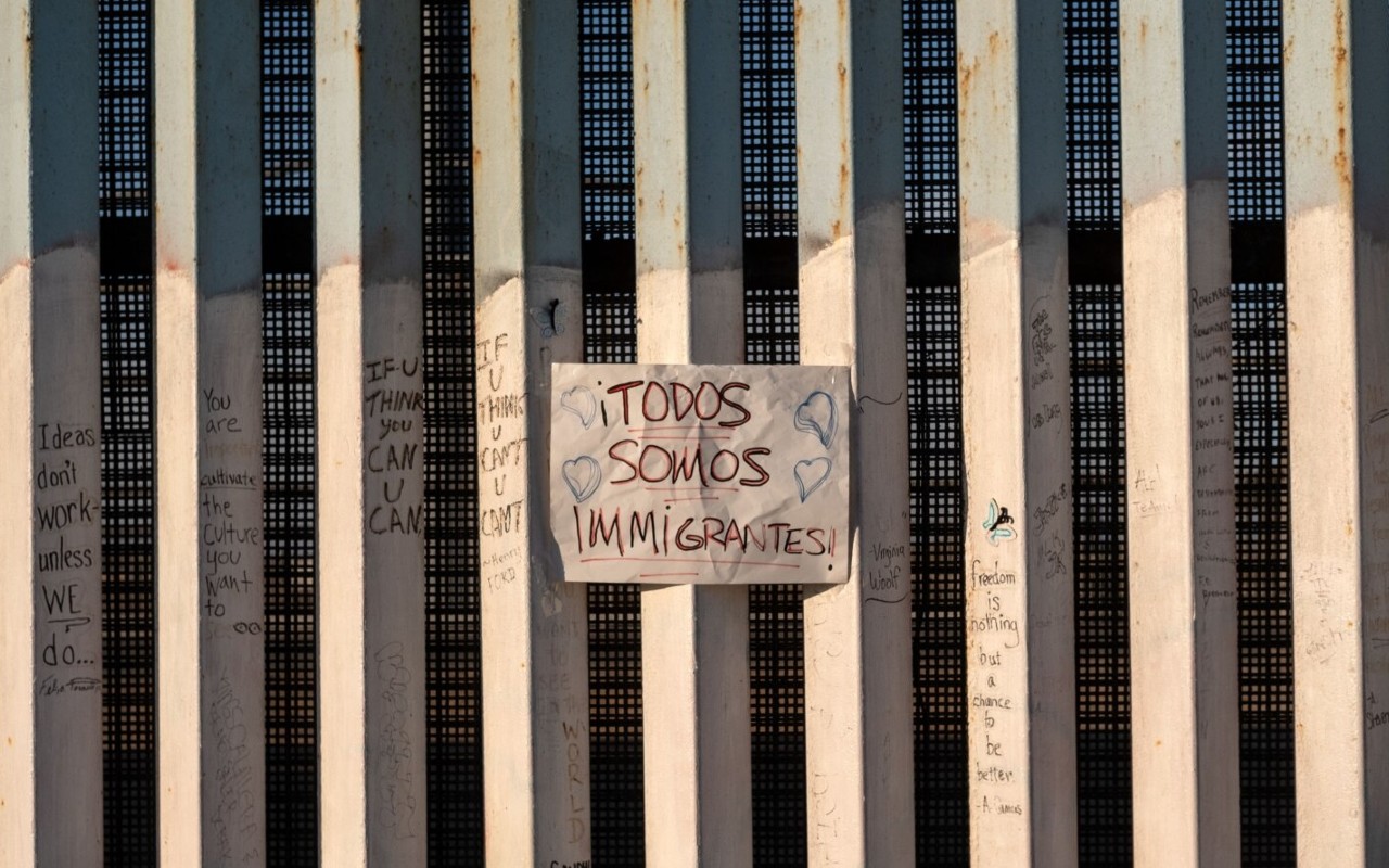 En la foto de archivo se ve un letrero en la frontera entre Estados Unidos y México que dice en español "todos somos migrantes", en Playas de Tijuana, noroeste de México. | Foto: AFP / Voz de América