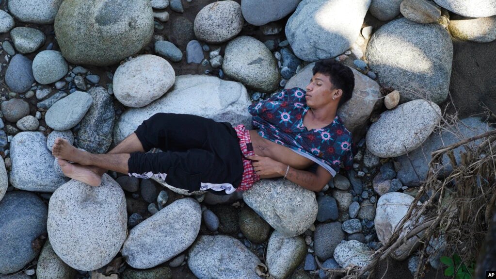 Un hombre que forma parte de una caravana migrante duerme a orillas del río Huixtla, estado de Chiapas, México, el martes 26 de octubre de 2021. | Foto: AP / VOA.