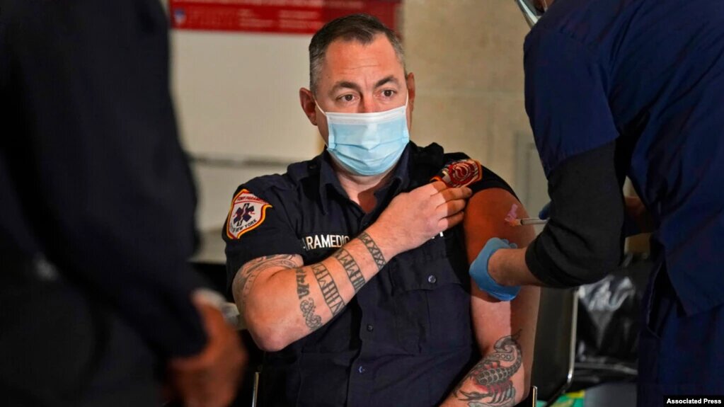 Un paramédico, miembro de los bomberos, recibe su vacuna en la ciudad de Nueva York. | Foto: VOA/AP.