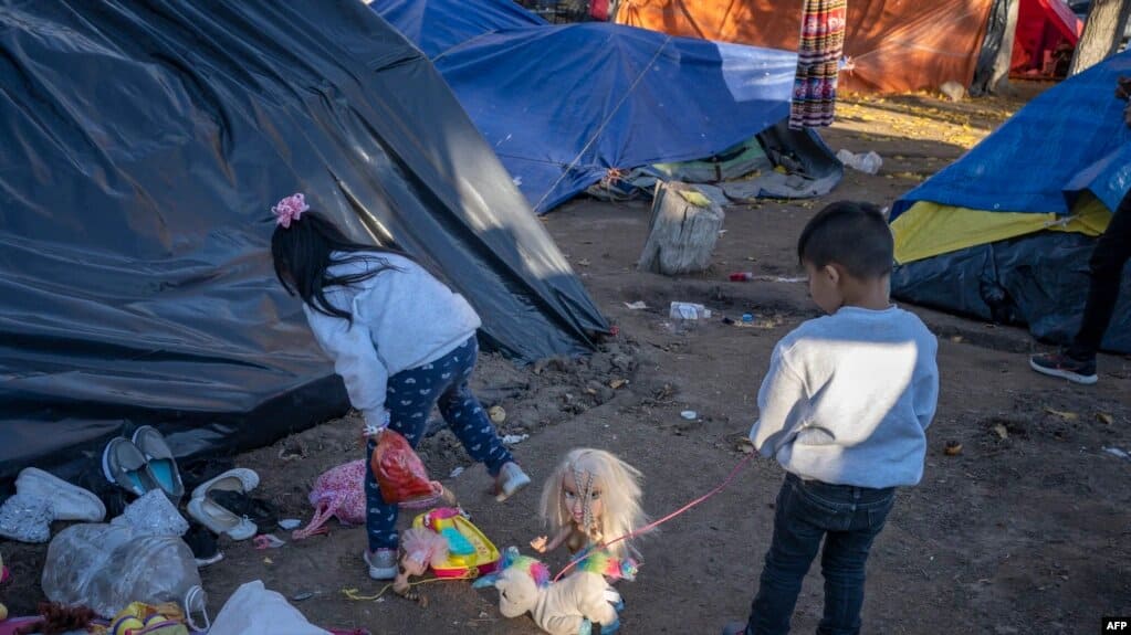 Dos niños migrantes juegan en Ciudad Juárez luego de que fueron devueltos luego de que la petición de asilo de su padre fuera rechazada, en diciembre de 2019. | Foto: VOA/AFP.
