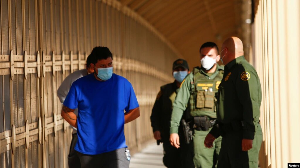 Migrantes son escoltados por agentes de la Patrulla Fronteriza en el Puente Fronterizo Internacional Lerdo Stanton para ser devueltos a México por el programa Quédate en México. | Foto: Reuters / VOA.