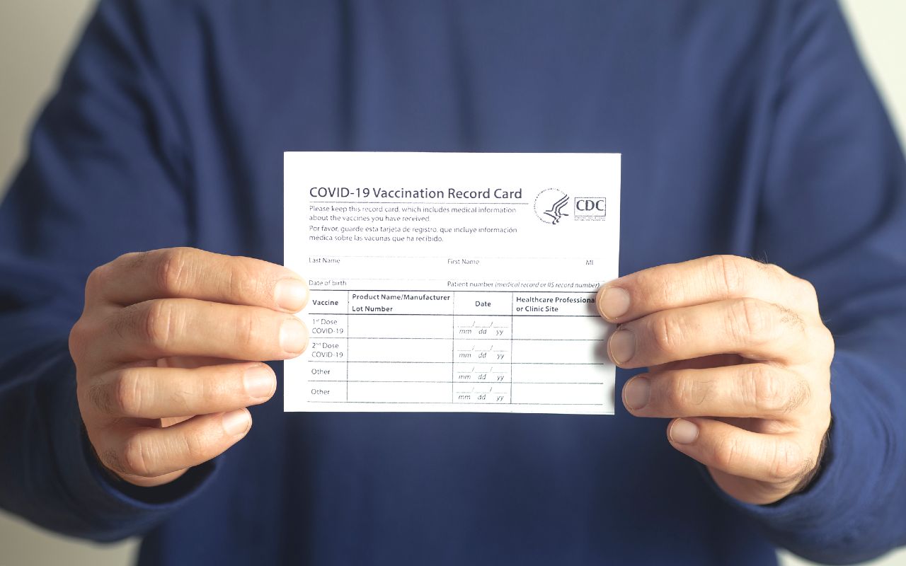 Una persona sostiene una tarjeta de vacunación de Covid-19. | Foto: Depositphotos