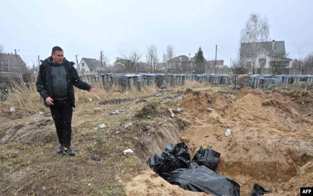 Con la guerra Rusia-Ucrania, un hombre muestra una fosa común con cadáveres en el poblado de Bucha, al noreste de Kiev, Ucrania, el 3 de abril de 2022. | Foto: VOA / AFP.