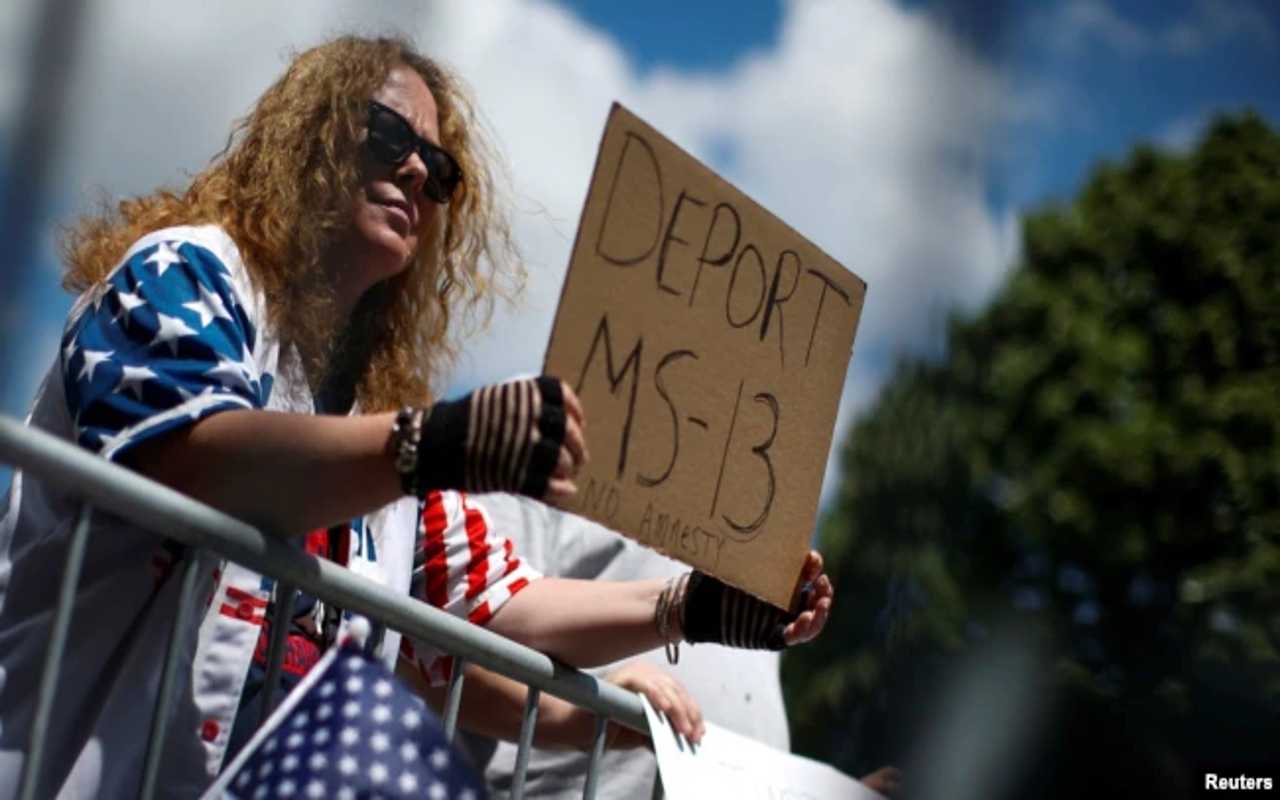 Una partidaria del expresidente Donald Trump sostiene una pancarta contra la MS-13 durante un foro sobre la Mara Salvatrucha (MS-13) con sede en América Central en el Centro de Seguridad Nacional Morrelly en Bethpage, Nueva York, EE. UU., el 23 de mayo de 2018. | Foto: VOA / Reuters.