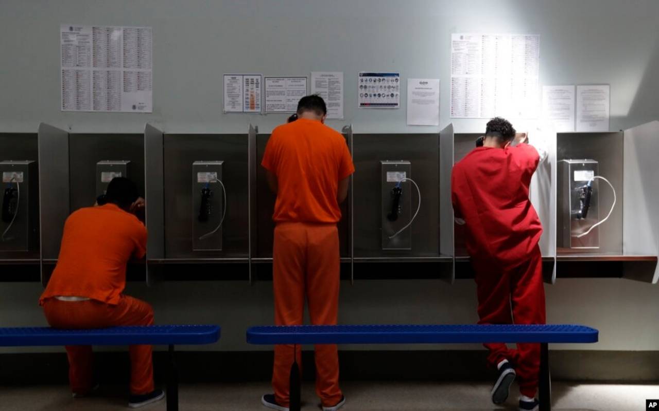 Unos detenidos hablan por teléfono en el centro de detención del Servicio de Control de Inmigración y Aduanas de Estados Unidos en Adelanto, California, en Estados Unidos. | Foto: VOA / AP.