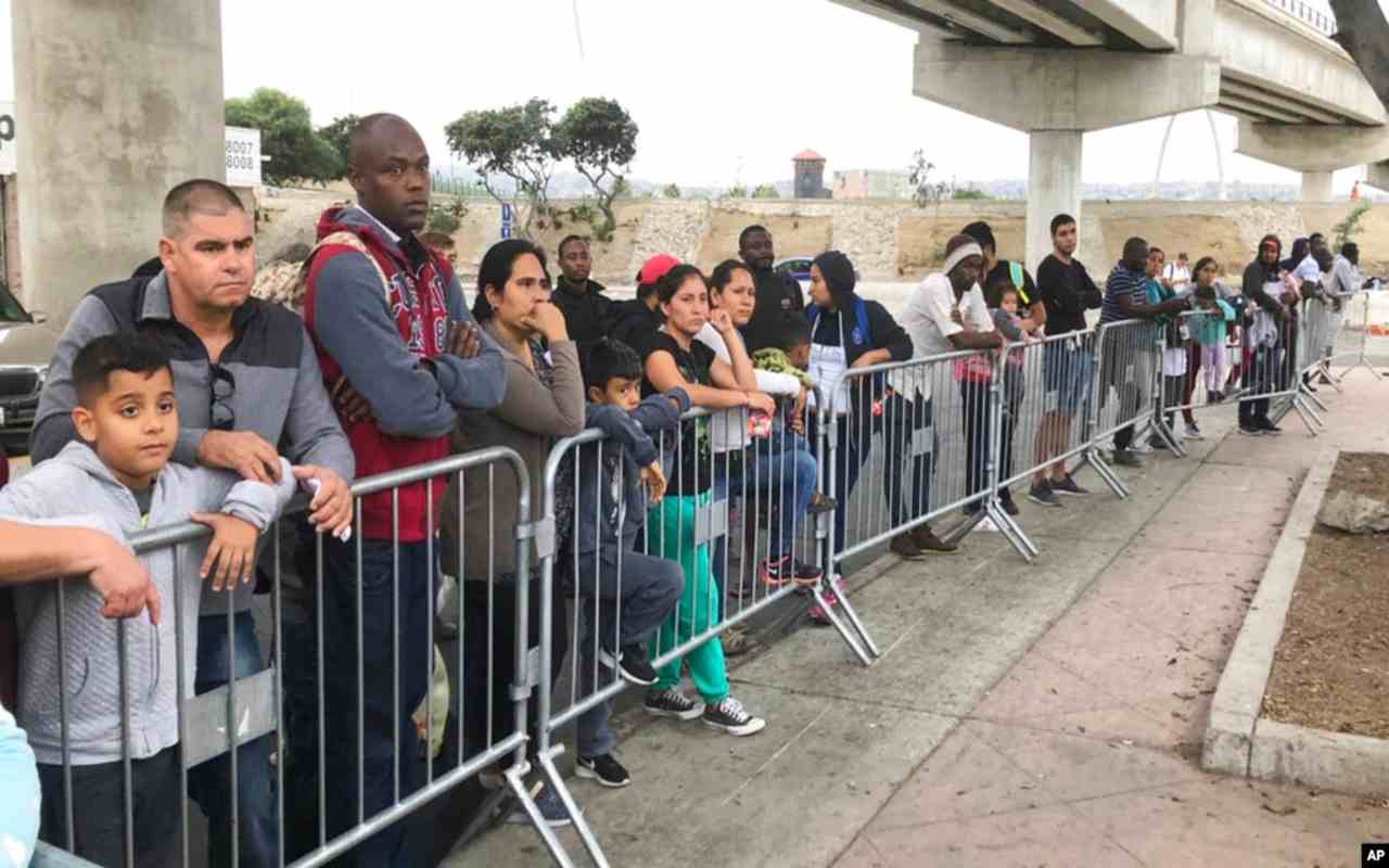 Solicitantes de asilo en Tijuana, México, escuchan si sus nombres son llamados en un cruce fronterizo en Estados Unidos tras el fin del programa Quédate en México. | Foto: VOA / AP.