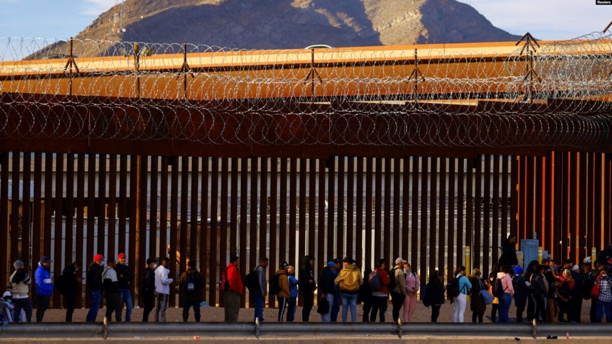 Migrantes hacen cola cerca de la valla fronteriza, después de cruzar el río Bravo, para solicitar asilo en Estados Unidos | Foto: Voz de América / Reuters