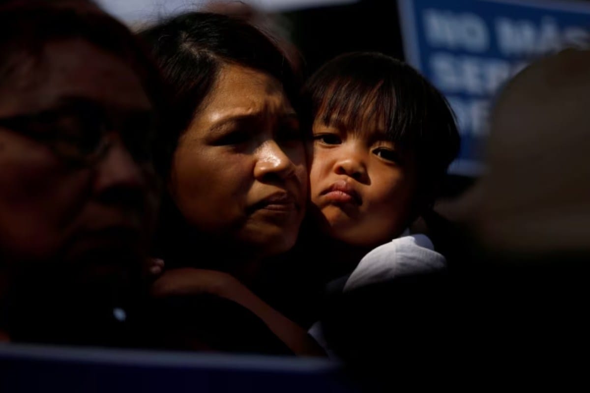 Un niño abraza a una mujer mientras la gente sostiene carteles para protestar contra la orden ejecutiva del presidente Donald Trump para detener y separar a las familias de los menores migrantes que cruzan la frontera. | Foto: Reuters / Voz de América