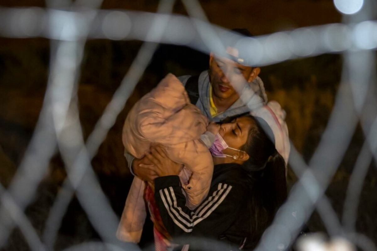 Una pareja de migrantes cargan a su bebé mientras se aproximan a una puerta en el muro fronterizo para solicitar asilo en Estados Unidos | Foto: AP / Voz de América