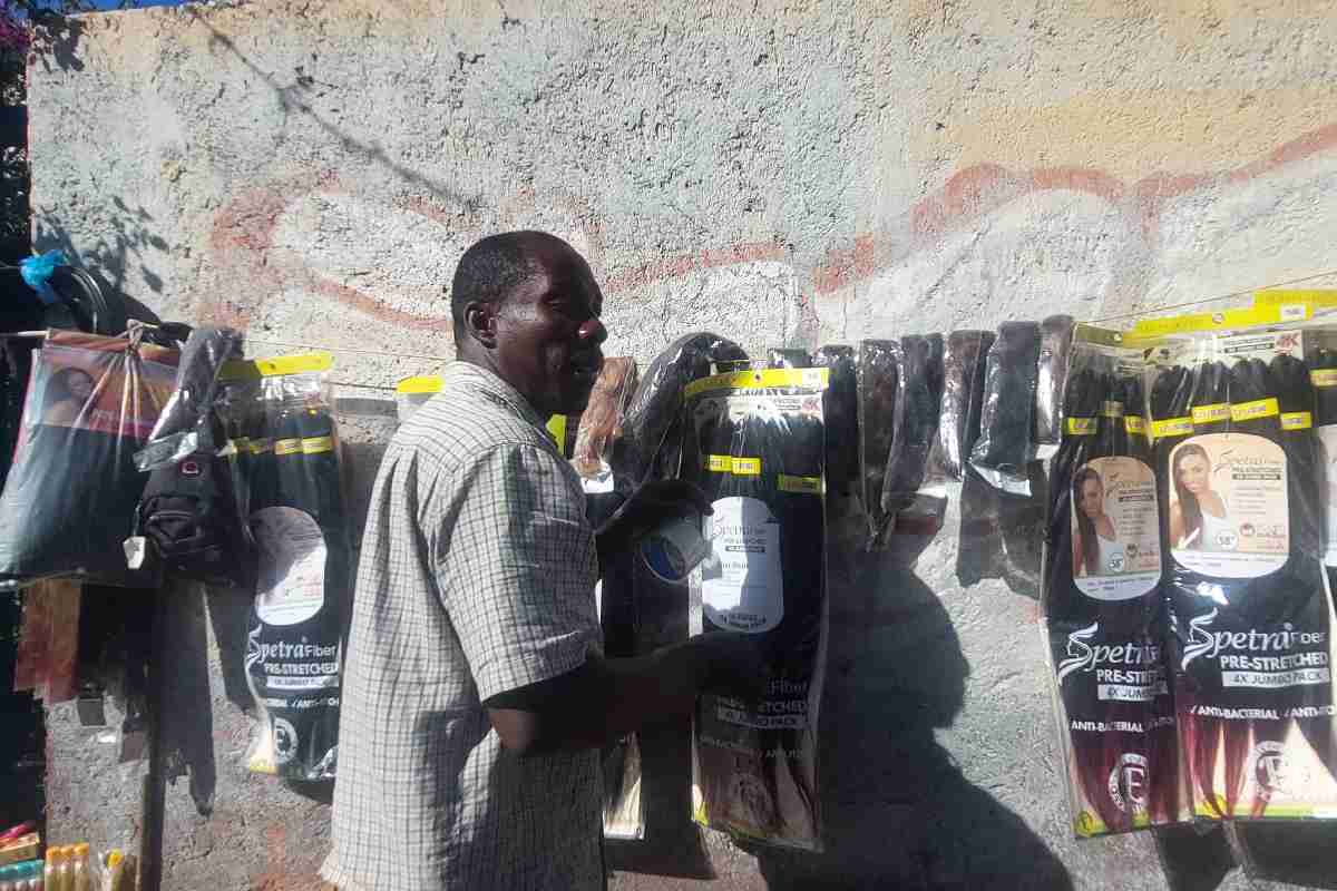 Joven haitiano hace trencitas y vende artículos de belleza en frente del bosque de Tláhuac | Foto. Valeria Acevedo